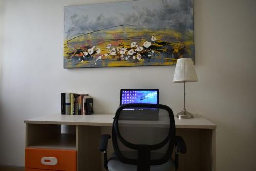 a desk with a laptop computer and a painting on the wall at MADRIGIO... a casa propria in Casamassima