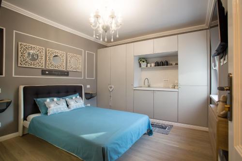 a bedroom with a blue bed and a kitchen at 62 Steps to Petit Bonheur in Bucharest