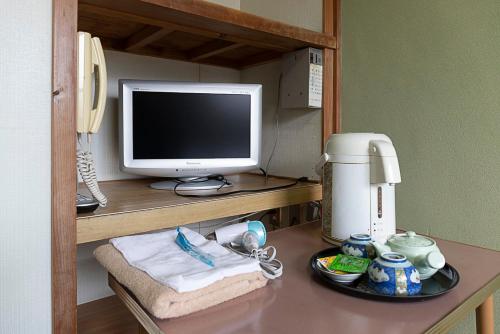 een bureau met een computermonitor en een koffiezetapparaat bij TSUKASA HOUSE English OK Kumano Kodo experience Lodge Close to station 無料駐車場あり in Tanabe