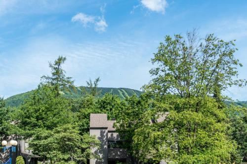 a building with trees and mountains in the background at INITIAL - L'OURS - Mont-Sainte-Anne in Beaupré