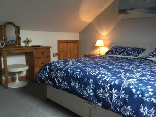 a bedroom with a blue bed and a dresser and a mirror at Tyddyn Perthi Farm in Llanberis