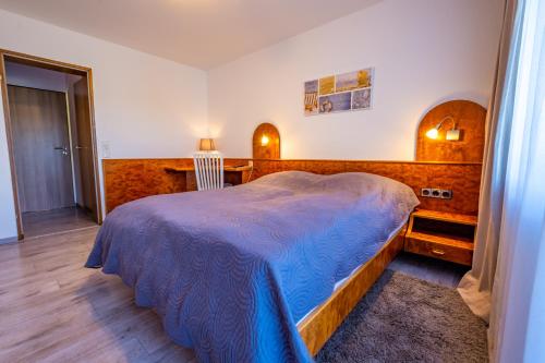 ein Schlafzimmer mit einem Bett mit einer blauen Decke darauf in der Unterkunft Hotel Klosterhof in Wehr
