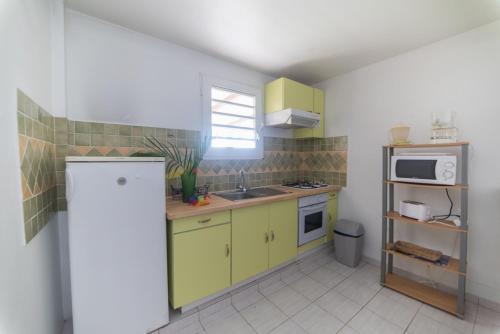 eine kleine Küche mit gelben Schränken und einer Mikrowelle in der Unterkunft Appartement Majo in Le Lamentin