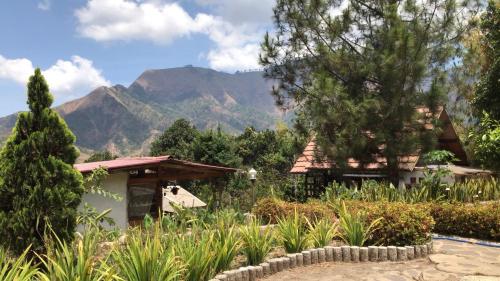a house with a mountain in the background at Sembalun Kita Cottage in Sembalun Lawang