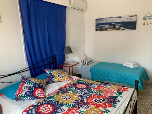 two beds in a room with blue curtains at Starfish Seaside Studio in Artemida