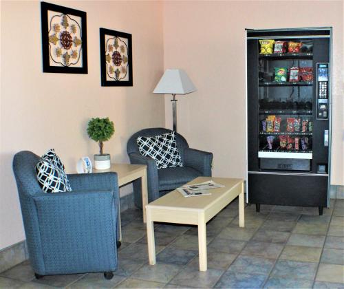 a living room with two chairs a table and a refrigerator at Knights Inn Payson in Payson