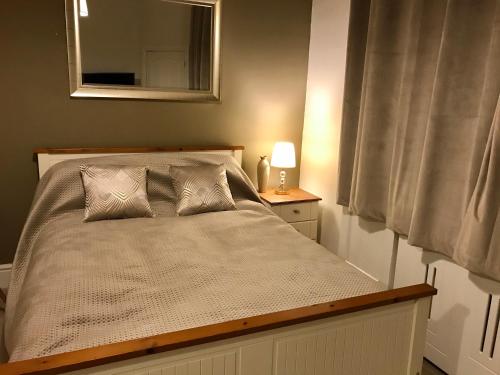 a bedroom with a bed with a mirror and a lamp at Velvet Nest 5 min walk from train station in Leamington Spa