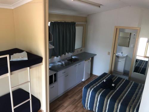 a small kitchen with a sink and a bed at Karumba Point Sunset Caravan Park in Karumba