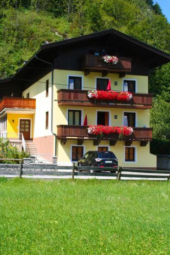 a house with flowers on the windows and a car in front at Apartments Landhaus Sonnheim in Lofer