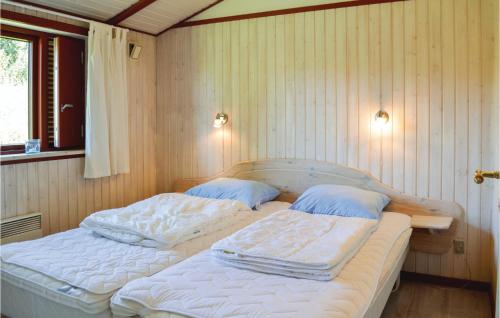 Habitación con 2 camas individuales y paredes de madera. en Nice Home In Dronningmlle With 3 Bedrooms And Wifi, en Dronningmølle