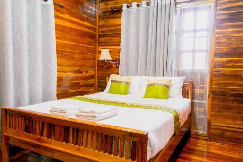 a bedroom with a bed with wooden walls and a window at Imsuk Homestay at Chiang Rai in Chiang Rai