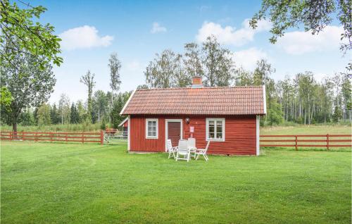 a small red house with two white chairs in the yard at Stunning Home In Vimmerby in Vimmerby