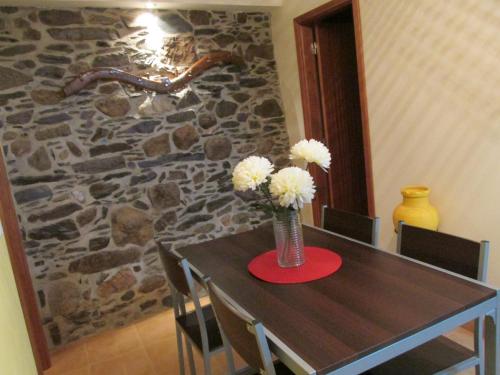 a table with a vase with white flowers on it at Casa Nazare in Vilar Torpim