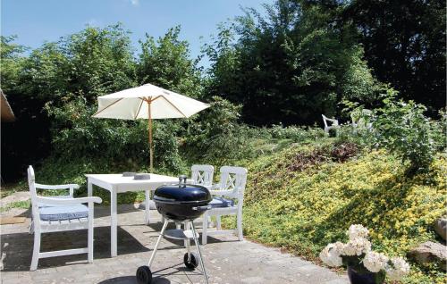 a grill and a table with chairs and an umbrella at One-Bedroom Holiday Home In Christiansfeld in Christiansfeld