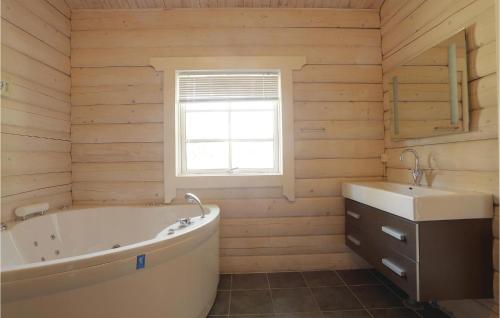 a bathroom with a tub and a sink at Holiday Home Frederiksvej Nexø Denm in Balke