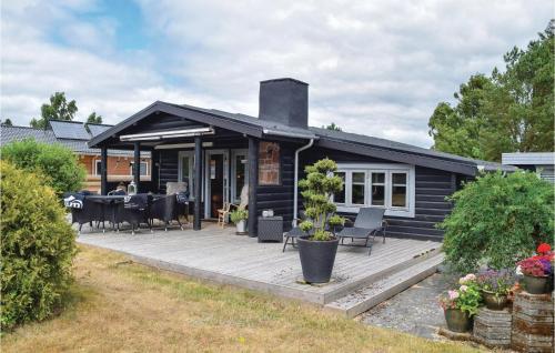 a black house with a large wooden deck at Holiday Home Ålykke Juelsminde I Denmark in Sønderby