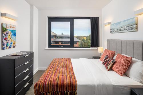 um quarto com uma cama, uma janela e uma cómoda em St Albans City Apartments - Near Luton Airport and Harry Potter World em Saint Albans