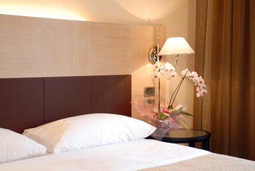 una habitación de hotel con una cama y un jarrón de flores en San Giorgio, Sure Hotel Collection by Best Western, en Forlì