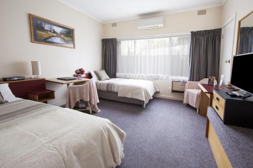a hotel room with two beds and a television at Redhill Cooma Motor Inn in Cooma