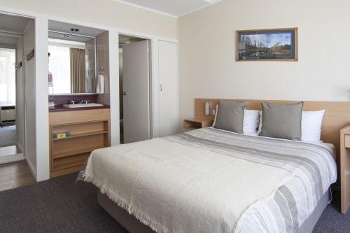 a bedroom with a large bed and a bathroom at Redhill Cooma Motor Inn in Cooma