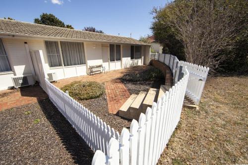 a white picket fence in front of a house at Redhill Cooma Motor Inn in Cooma