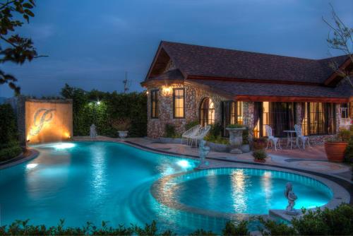 a swimming pool in the backyard of a house at night at Chateau de Prim Khao Yai in Ban Sap Phlu