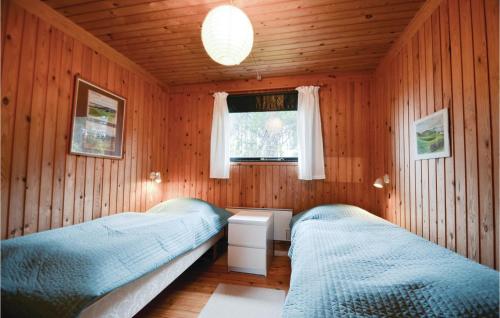 two beds in a room with wooden walls and a window at Mugge in Ebeltoft