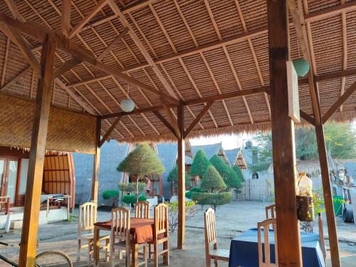 un restaurant avec une table et des chaises sous un toit dans l'établissement Sunset Beach Bungalow, à Gili Meno
