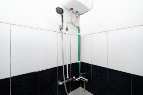 a shower in a bathroom with black and white tiles at Super OYO 1565 Palebon Residence in Semarang