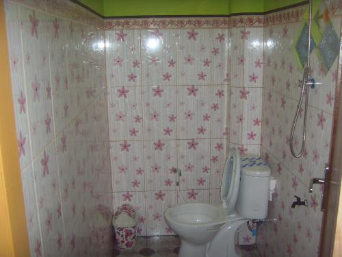 a bathroom with a toilet and pink flowers on the wall at Cahyo Homestay Bromo in Bromo