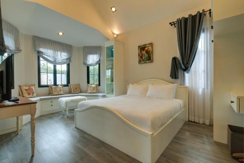 a bedroom with a white bed and a desk and a desk at Chateau de Prim Khao Yai in Ban Sap Phlu