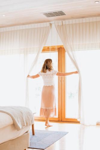 a woman in a dress is standing at a window at Yallingup Villas in Yallingup