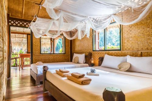 two beds in a room with windows at River Kwai Jungle Rafts - SHA Extra Plus in Sai Yok