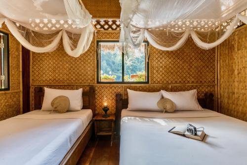 two beds with shoes on them in a room at River Kwai Jungle Rafts in Sai Yok