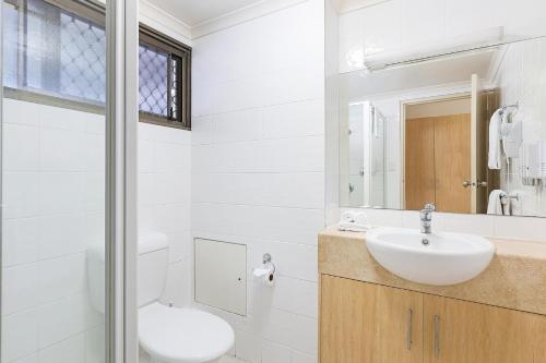 a bathroom with a sink and a toilet and a mirror at Reef Gateway Hotel in Airlie Beach