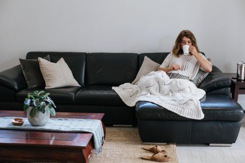 a woman sitting on a couch with a blanket at Yallingup Villas in Yallingup
