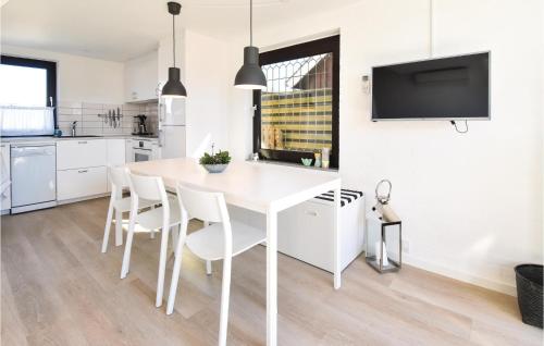 a white kitchen with a white dining room table and chairs at One-Bedroom Holiday Home In Otterup in Otterup