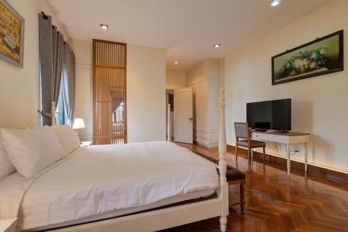 a bedroom with a bed and a desk and a television at Chateau de Prim Khao Yai in Ban Sap Phlu