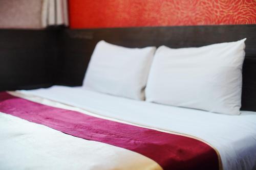 a bed with white pillows and a red wall at Happy Hotel in Kaohsiung