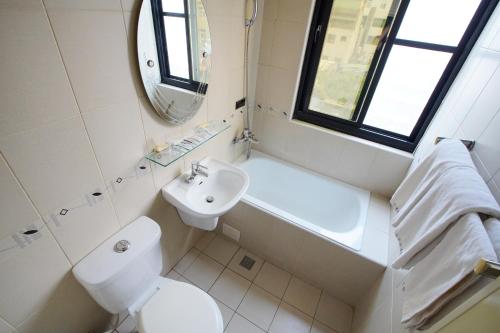 a bathroom with a toilet and a sink and a mirror at Happy Hotel in Kaohsiung