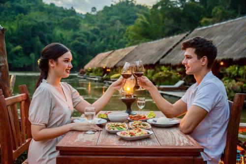 a man and woman sitting at a table with glasses of wine at River Kwai Jungle Rafts in Sai Yok