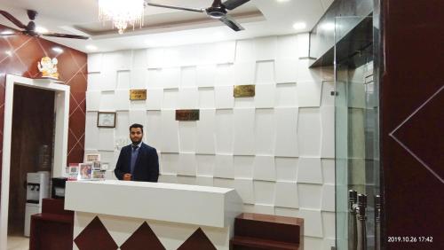 a man standing behind a counter in a lobby at Hotel Amar Leela in Dehradun