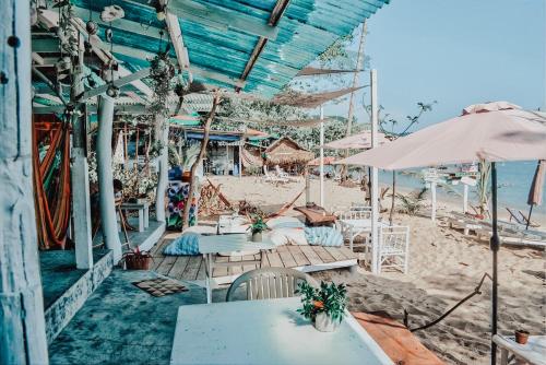 a cafe on the beach with tables and umbrellas at Indie Beach Bungalows in Ko Chang