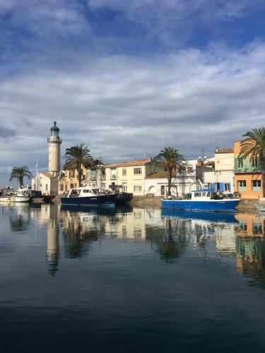 un grupo de barcos en un cuerpo de agua con un faro en Rêve bleu, en Le Grau-du-Roi