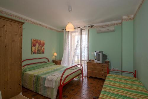 a bedroom with two beds and a tv and a window at Agriturismo Nardini in Rodi Garganico