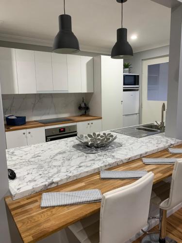 a kitchen with white cabinets and a marble counter top at The Hutt on Mandurah Marina in Mandurah