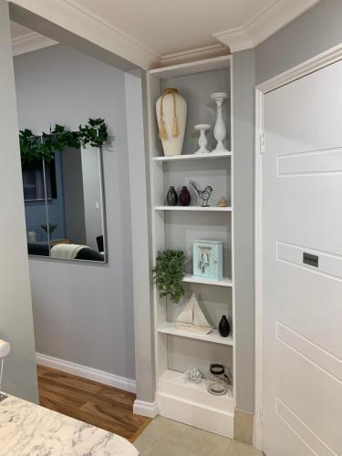 a room with white shelves with vases and a mirror at The Hutt on Mandurah Marina in Mandurah