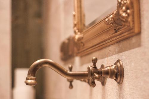 a bronze faucet on a wall with a mirror at Vila Terrasse in Košice