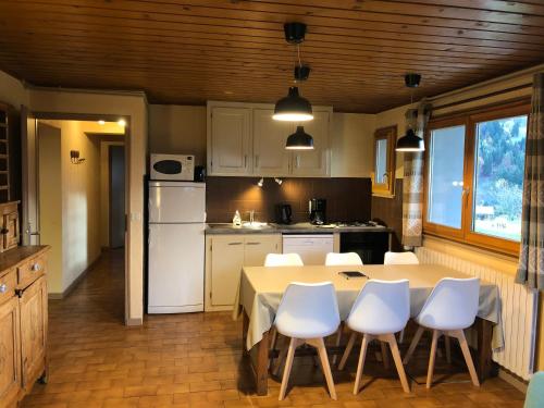 une cuisine avec une table et des appareils électroménagers blancs dans l'établissement Chalet la Tovasse, à Notre-Dame-de-Bellecombe