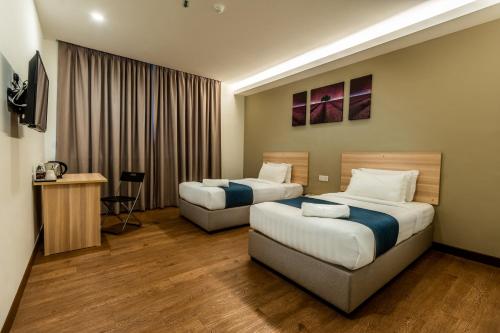 a hotel room with two beds and a television at 1 Orange Hotel KLIA & KLIA2 in Sepang